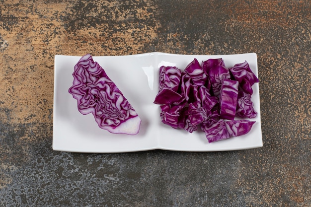 A piece of cabbage next to finely chopped cabbage in the bowl, on the marble surface