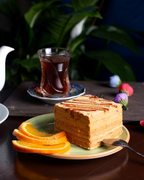 Piece of cake served with orange slices served with tea