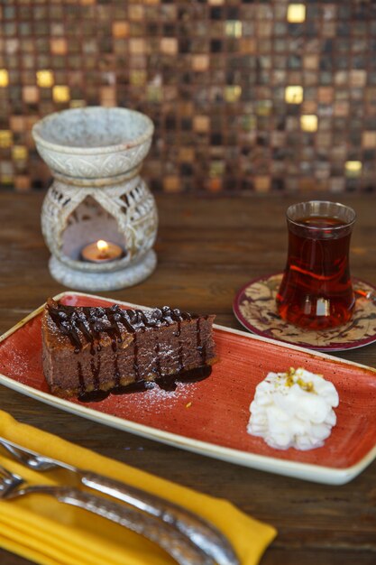 Piece of chocolate brownie served with cream and tea