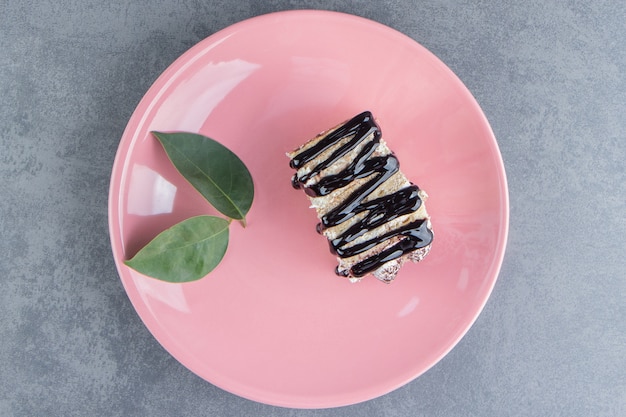 Free photo a piece of chocolate cake with leaf on a pink plate