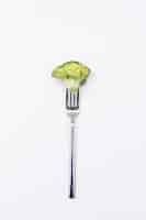 Free photo piece of fresh broccoli on fork isolated on white surface