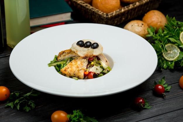 A piece of grilled fish fillet with green salad and berries in a white plate.