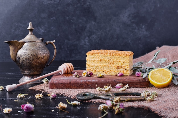 A piece of honey cake with dried flowers and classic teacup on marble table. 