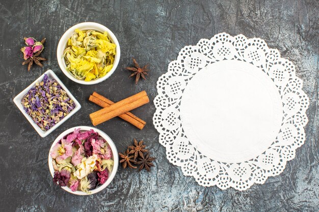 Free photo a piece of lace with bowls of dry flowers on grey ground