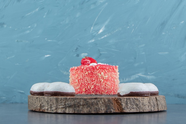 Free photo piece of strawberry cake and biscuits on wood piece.