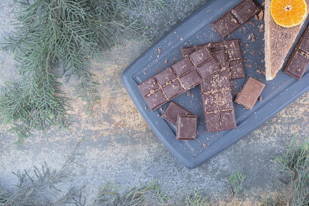 A piece of tasty cake with sliced chocolate on dark board. High quality photo