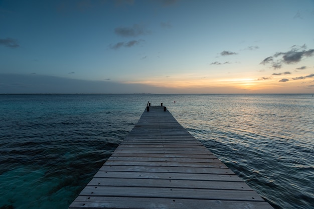 Free photo pier leading to the breathtaking sunset reflecting in the ocean in bonaire, caribbean