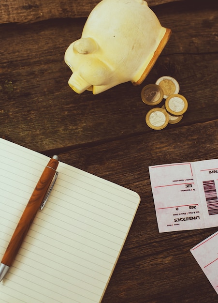 Free photo piggy bank and notepad on wooden table