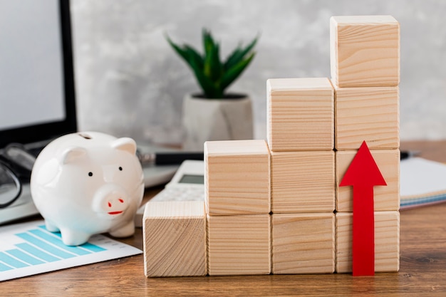 Piggy bank with wooden growth blocks and arrow