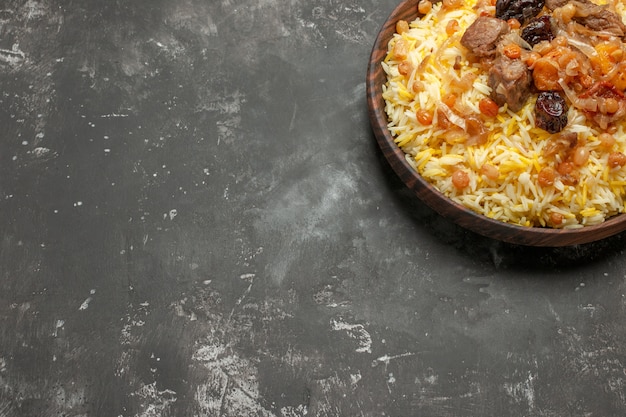 Free photo pilaf wooden bowl of an appetizing rice with meat on the table