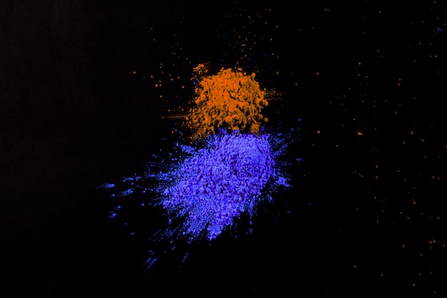 Pile of blue and orange indian holi colors arranged on black surface