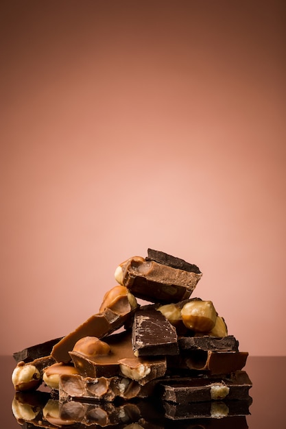 Free photo pile of broken chocolate on table against brown studio background