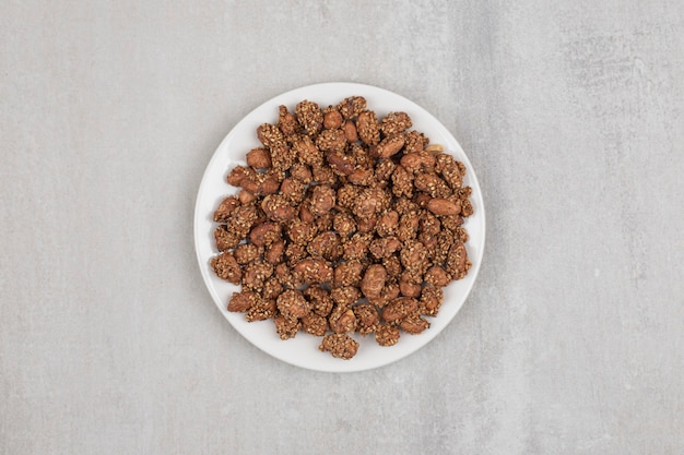 Pile of candies with sesame seeds on white plate.