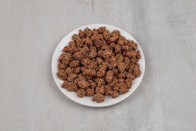 Pile of candies with sesame seeds on white plate.