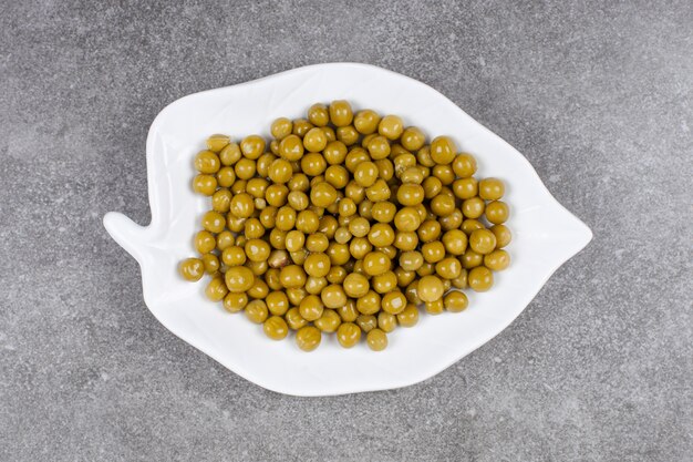 Pile of canned peas on white plate