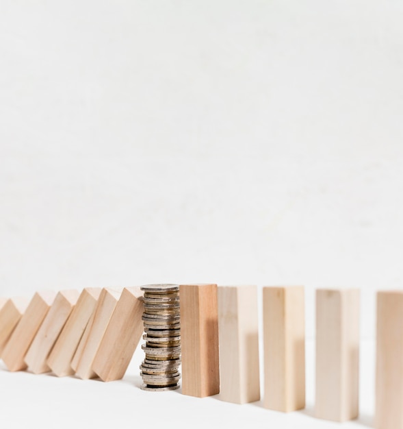 Free Photo pile of coins stopping fallen wooden pieces