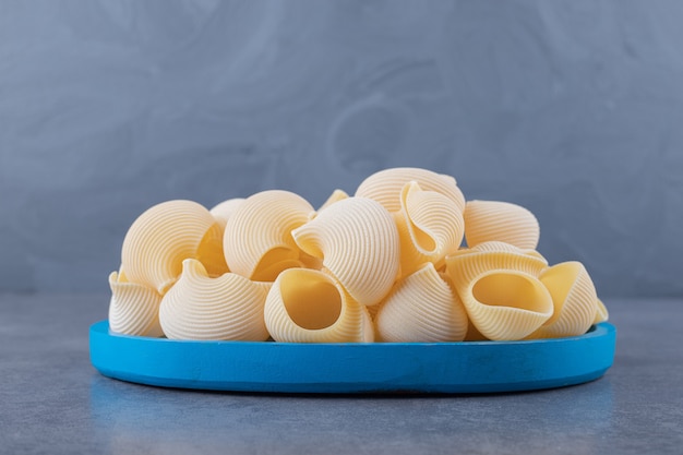 Free photo pile of conchiglie pasta on blue plate.