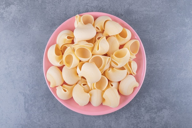 Free photo pile of conchiglie pasta on pink plate.