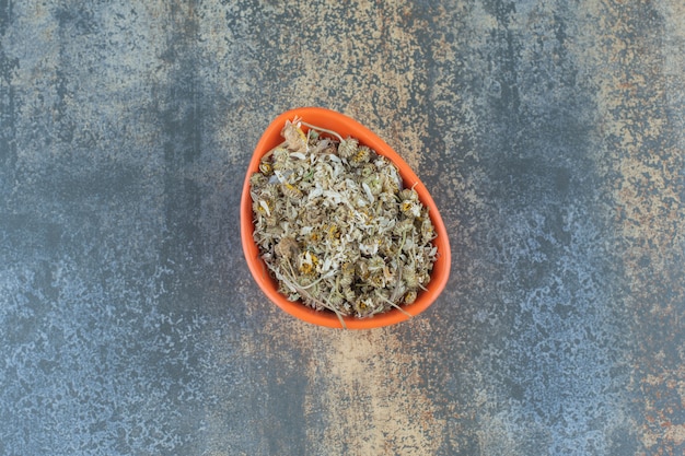 Free photo pile of dried chamomile in orange bowl.