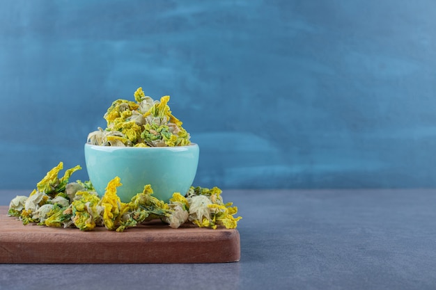 Free photo pile of dried flowers on wooden board and in bowl.