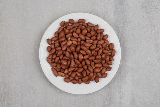 Pile of fresh peanuts on white plate.