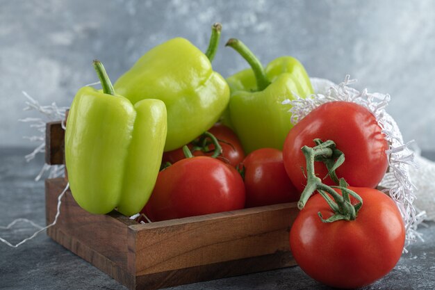 Pile of fresh vegetables on wooden basket over grey background. 