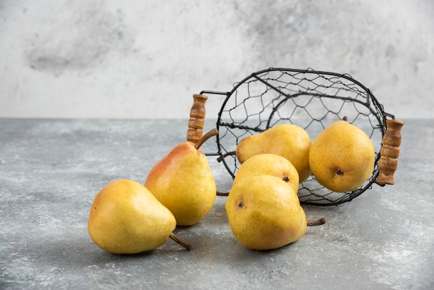 Free Photo pile of fresh yellow pears in metal bucket on marble surface. 