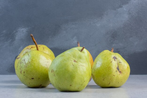 Pile of green pears on grey background.