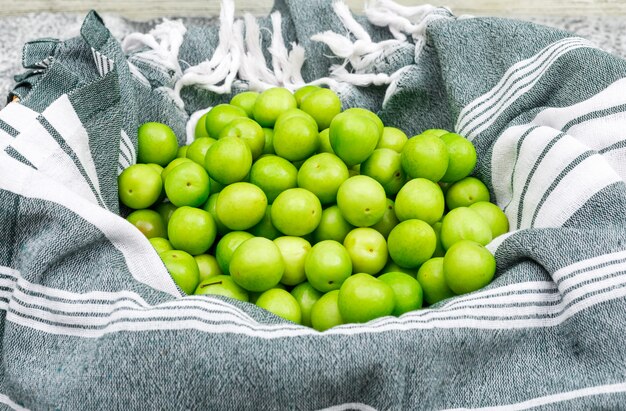 Free photo pile of greengages on kitchen towel and grunge, side view.