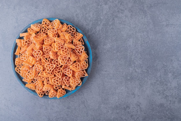 Free Photo pile of heart-shaped pasta on blue plate.