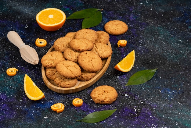 Free Photo pile of homemade fresh cookies and half cut or sliced orange over dark table.