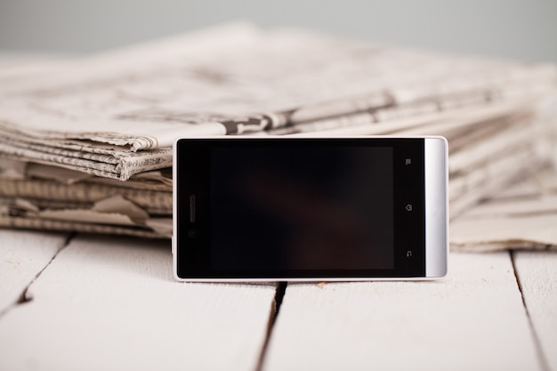 Free photo pile of newspapers with smartphone on it