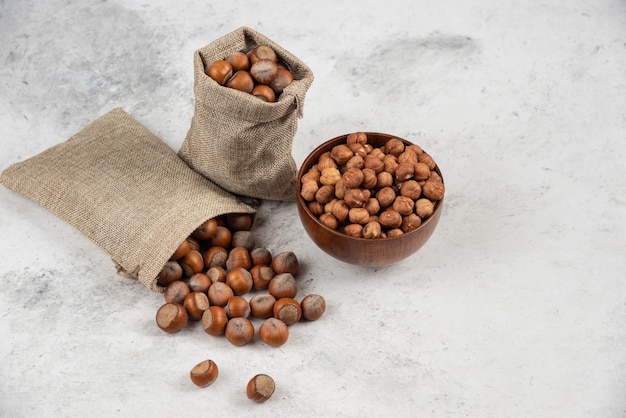 Pile of organic shelled and kernels of hazelnuts in burlap and in bowl. 