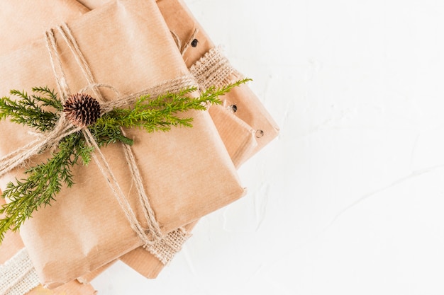 Pile of present boxes in craft paper with coniferous branch