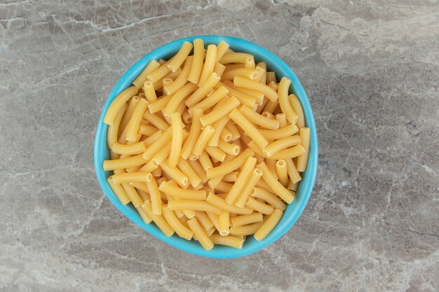 Pile of raw macaroni in blue bowl