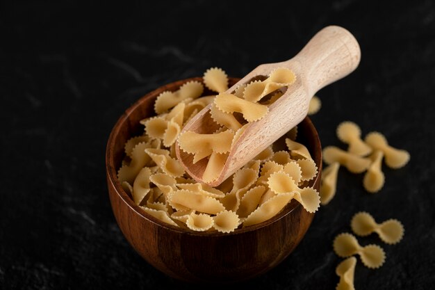 Pile of raw macaroni in wooden bowl. 