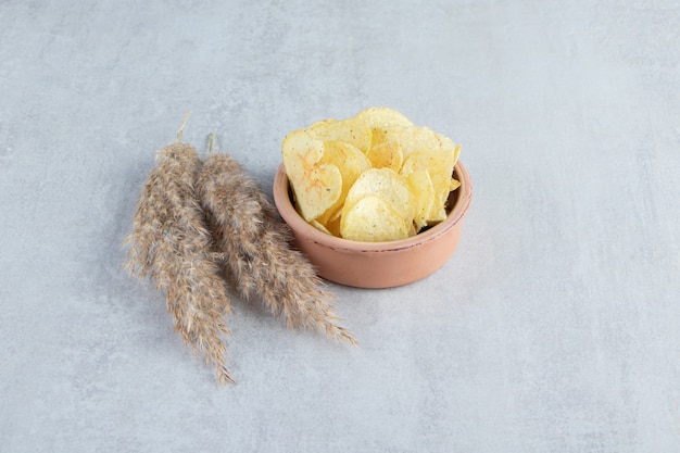 Pile of salted crispy chips placed in bowl on stone.