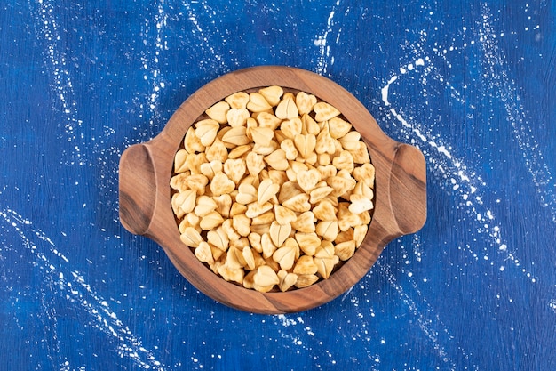 Free photo pile of salted heart-shaped crackers placed on wooden board.