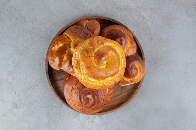 Pile of sweet buns, on a small tray on marble table.