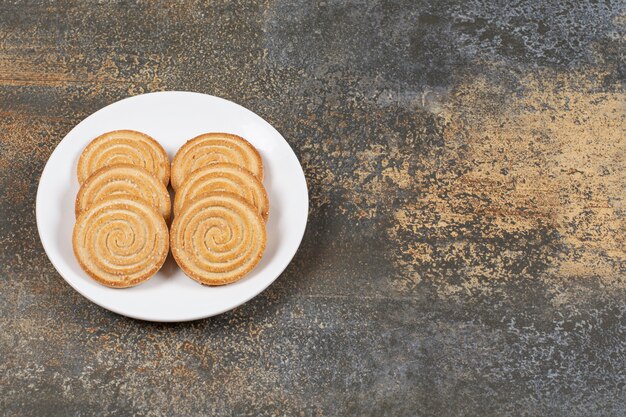 Pile of tasty round biscuits on white plate.