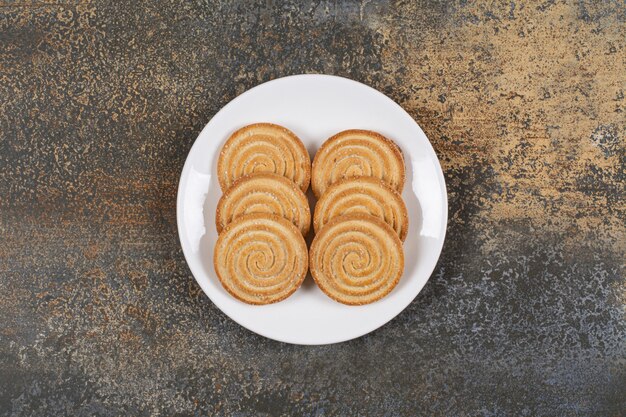 Pile of tasty round biscuits on white plate.