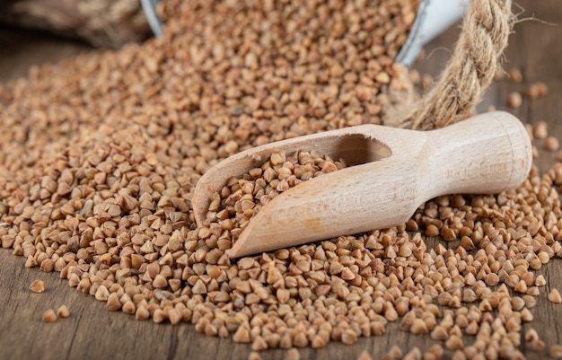 Free photo pile of uncooked buckwheat on wooden spoon