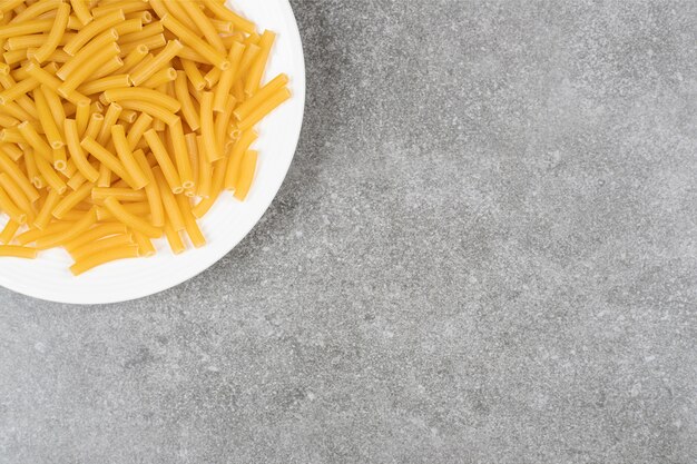 Pile of uncooked pasta on white plate