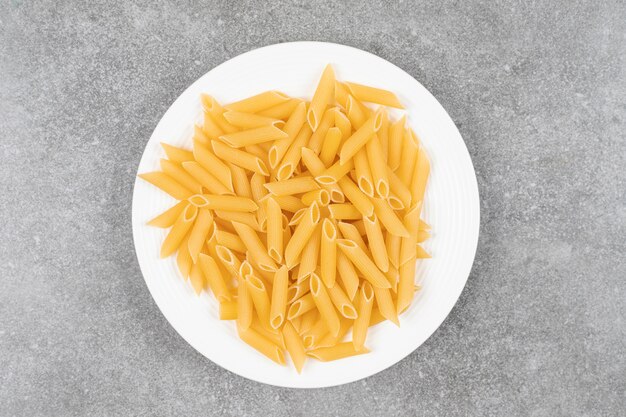 Pile of uncooked pasta on white plate