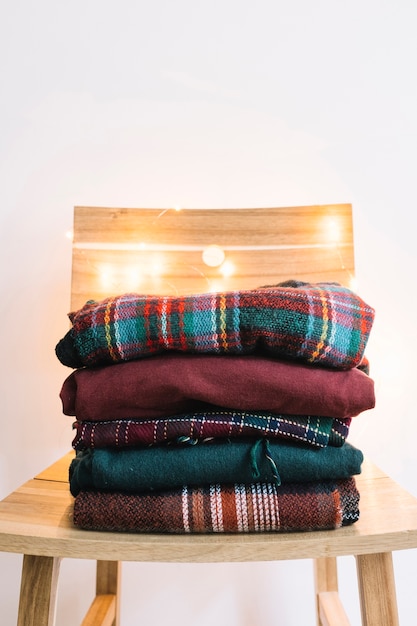 Free Photo pile of winter sweaters on wooden chair 