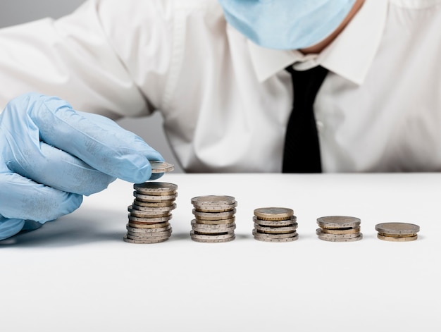 Free Photo piles of coins and man wearing protection gloves