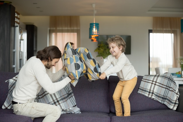 Free photo pillow fight between father and little son in living room