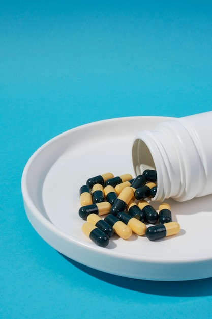 Free photo pills container on blue background high angle