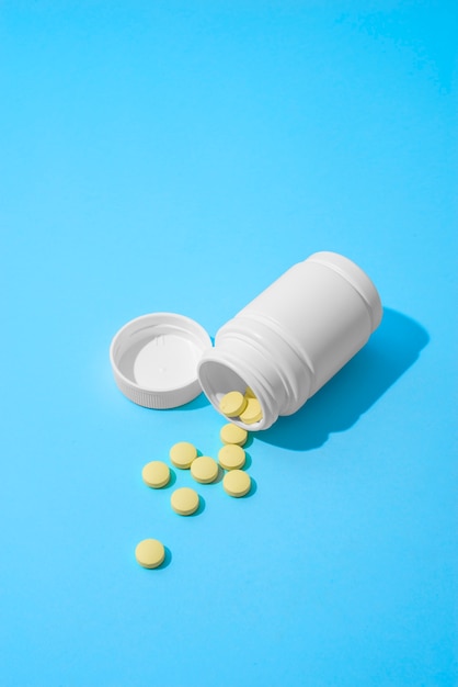 Pills container on blue background high angle