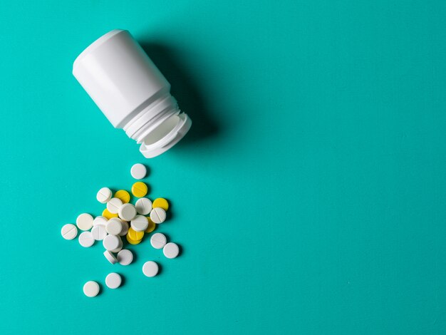 Pills and pill bottle on a cyan blue background. flat lay.